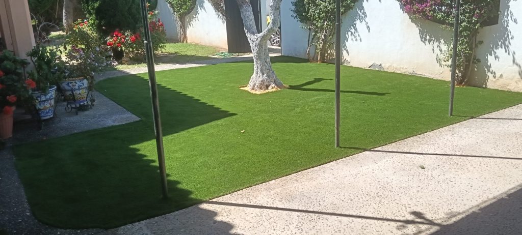 Instalación de césped artificial terminada junto a palmera - Limcesped Sevilla